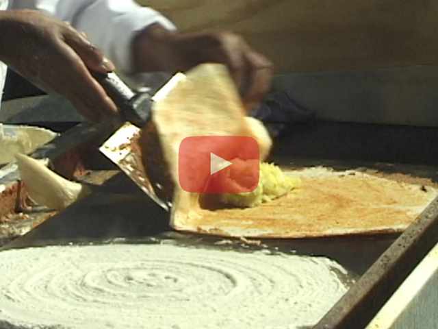 Play button showing dosa on grill being folded over filling.